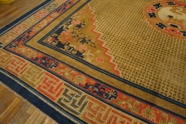 Intricate gold, coral, and navy rug displaying complex borders and a lattice field on wood planks.