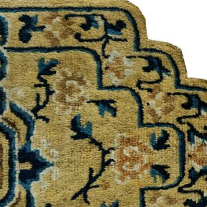 Textured, scalloped rug corner features gold pile with blue and brown traditional floral designs.