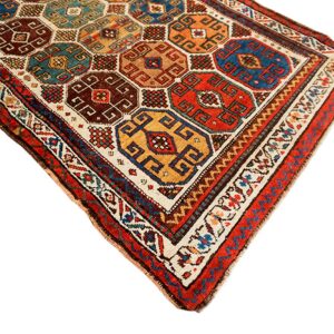 Richly colored rug with geometric octagons and squares in red, blue, gold, and brown on white.