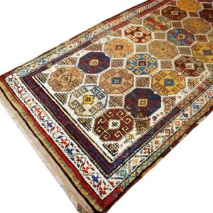 Runner rug displaying geometric octagonal medallions in deep blue, brown, yellow, and red on a cream ground.