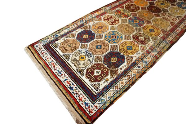Runner rug displaying geometric octagonal medallions in deep blue, brown, yellow, and red on a cream ground.