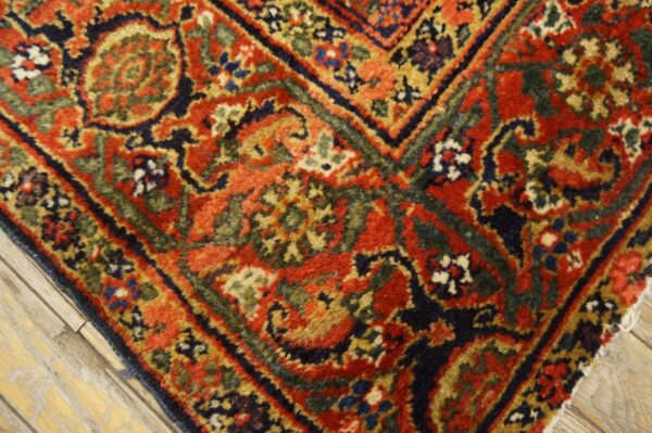 Ornate red, navy, and green traditional rug with high pile resting on distressed light wood floor.