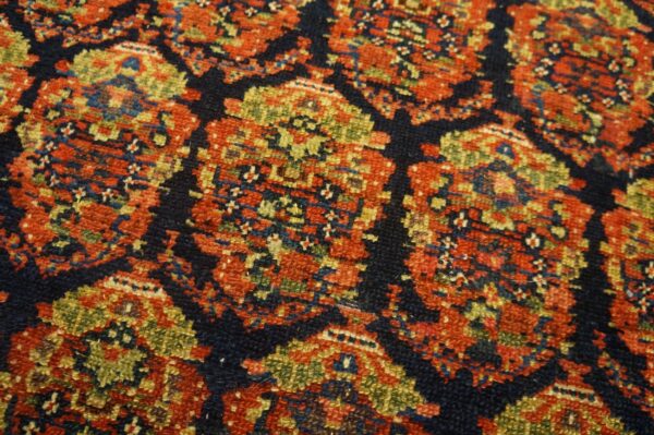 Traditional rug texture detailed with complex geometric medallions in rust, olive, and navy blue.