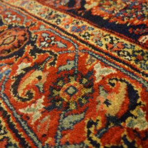 Ornate high-pile rug detail showing scrolling patterns in dark red, navy blue, and gold tones.