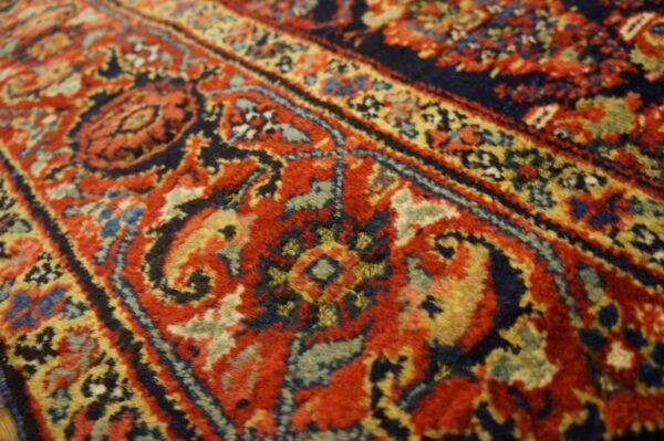 Ornate high-pile rug detail showing scrolling patterns in dark red, navy blue, and gold tones.