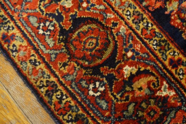 Ornate, medium-pile rug detail showing red, navy, teal, and yellow intricate patterns on light wood planks.