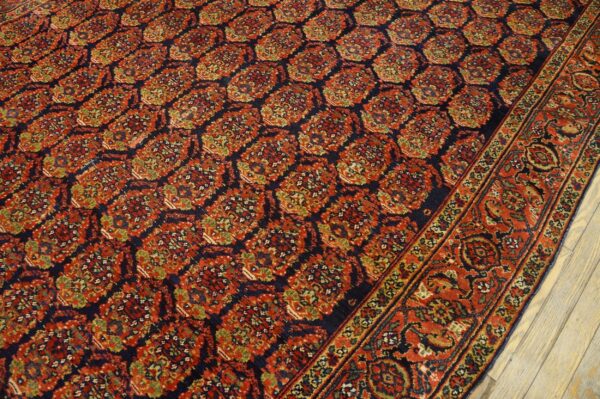 Intricate red, navy, and green patterned rug with a wide border on whitewashed wooden floorboards.