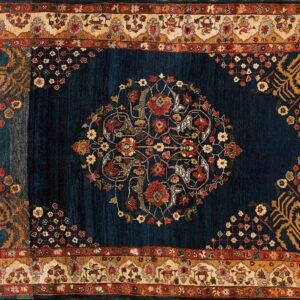 Dark indigo rug featuring a large floral medallion surrounded by elaborate cream, red, and gold borders.