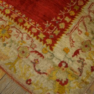 Textured red and beige high-pile rug featuring yellow floral motifs rests on weathered wood planks.
