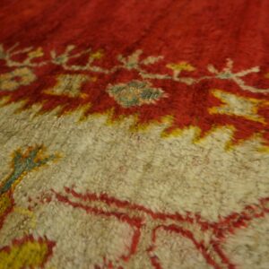 Close view of a shaggy rug pattern in red and beige with bright yellow and teal accents.