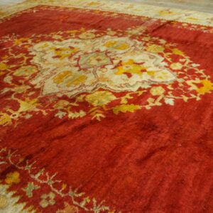 Deep red high-pile rug with an ornate central medallion in cream, gold, and muted green on light flooring.
