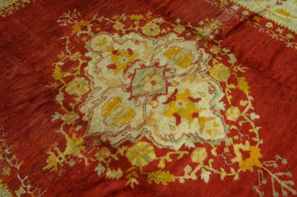 Low pile rug with a red field surrounding a stylized cream, yellow, and green floral center.