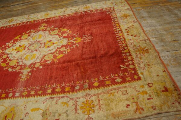Red and cream rug with a yellow traditional medallion pattern covers rustic wooden plank flooring.