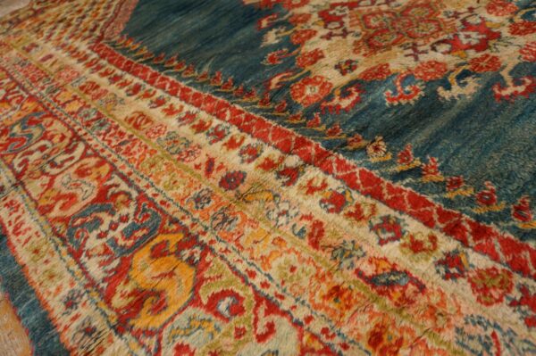 Close-up of a high-pile rug showing red, blue, cream, and gold traditional motifs across the field and striped borders.