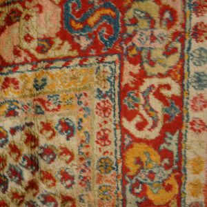High pile rug detail showing ornate red, teal, yellow, and cream traditional patterns and borders.