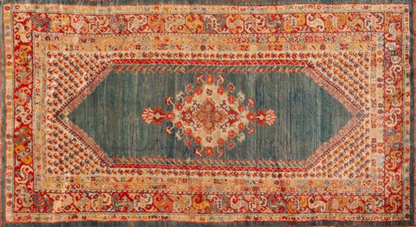 Ornate medallion rug featuring a striated teal ground and borders in red, cream, and gold tones.