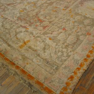 A textured beige rug with high pile, orange accents, and pink pattern rests on rustic wood floors.