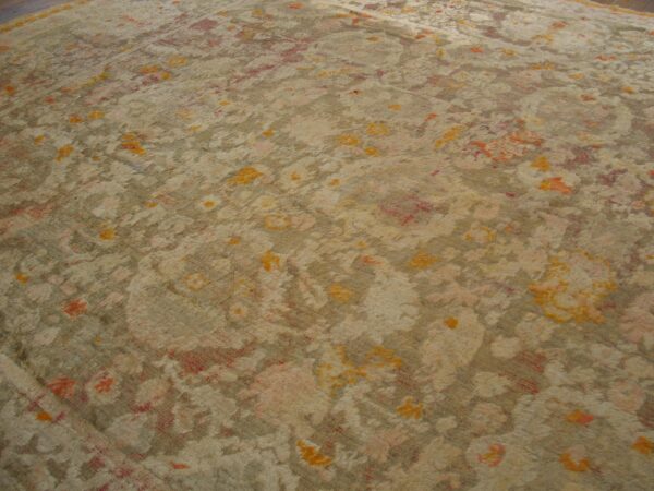 Fuzzy, high-pile rug with faded floral patterns in muted beige, tan, orange, and soft red.