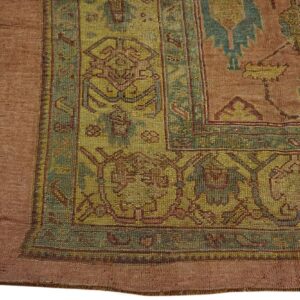 Close-up of a rug corner with geometric patterns in rust, olive, and teal colors.