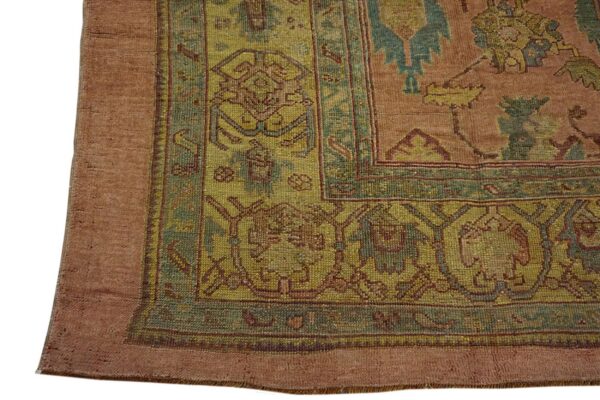 Close-up of a rug corner with geometric patterns in rust, olive, and teal colors.