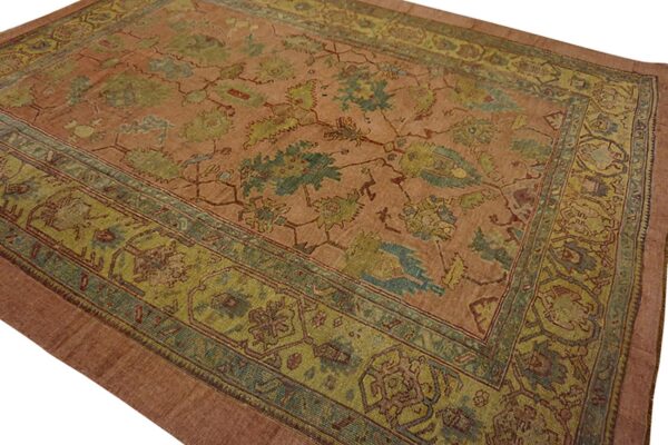 Low-pile rug with a rust field and highly ornate green and blue-green traditional border patterns.