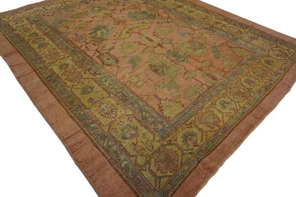 Low-pile rug featuring a rose field with large stylized floral motifs in muted greens and teal.