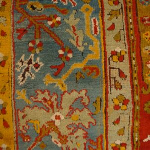 High-pile rug with complex floral patterns in teal, red, yellow, and sage on distressed wood floors.