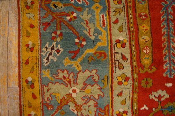 High-pile rug with complex floral patterns in teal, red, yellow, and sage on distressed wood floors.