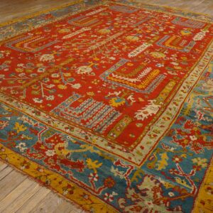 Ornate red, teal, and gold patterned rug with a visible high pile sits on light colored wood floorboards.