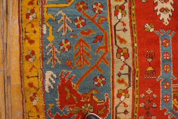 Close-up of a high pile rug in red, blue, and yellow on distressed wooden floorboards.