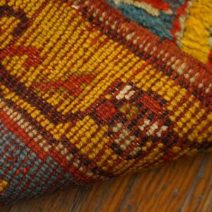 A folded multicolored rug shows tight weaving in red, yellow, and blue, contrasting with a shaggy yellow pile.
