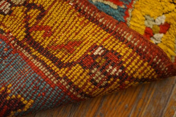 A folded multicolored rug shows tight weaving in red, yellow, and blue, contrasting with a shaggy yellow pile.