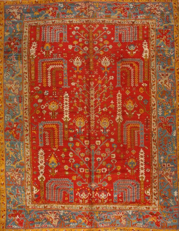 Ornate red rug featuring a central stylized tree motif surrounded by intricate blue and gold borders.