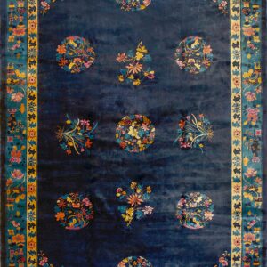 Deep indigo rug with nine colorful floral medallions, corner sprays, and an elaborate teal and yellow border.