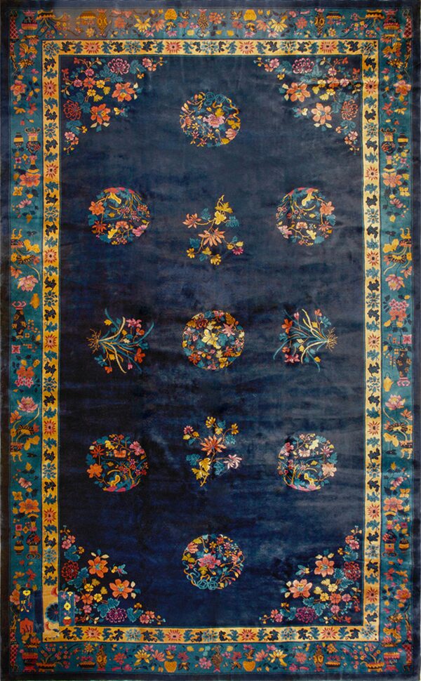 Deep indigo rug with nine colorful floral medallions, corner sprays, and an elaborate teal and yellow border.