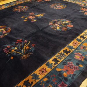 Plush dark blue rug with colorful scattered floral designs and a teal and mustard yellow border.