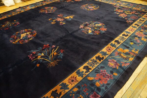 Plush dark blue rug with colorful scattered floral designs and a teal and mustard yellow border.