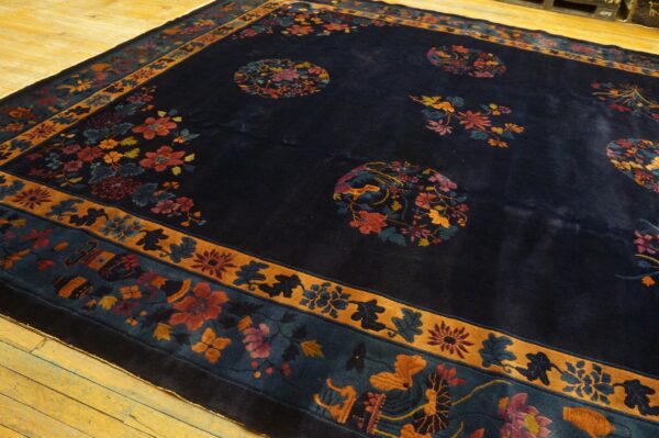Navy high-pile floral rug with multicolored medallions and thick borders rests on light wood flooring.