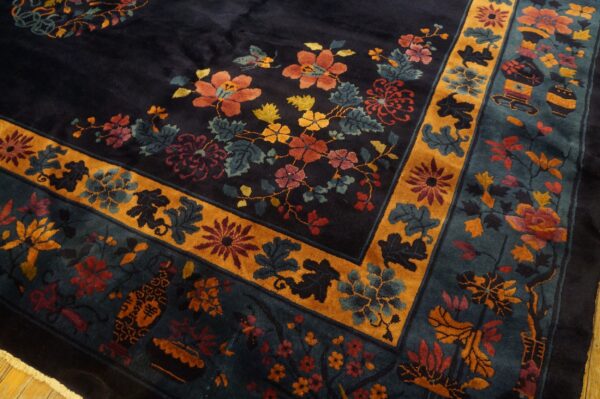 A dark blue rug with orange, red, and teal florals, featuring a prominent gold decorative border.