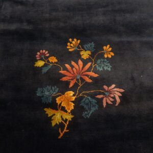 A dark blue pile rug featuring a stylized cluster of orange, pink, and yellow floral designs.