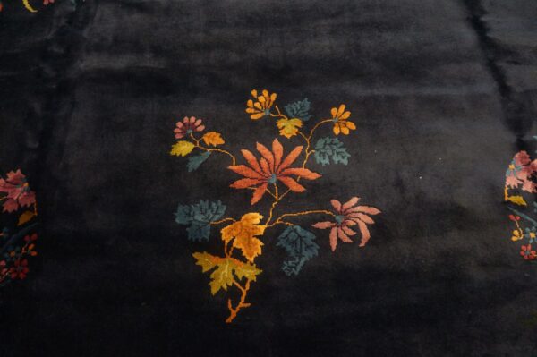 A dark blue pile rug featuring a stylized cluster of orange, pink, and yellow floral designs.