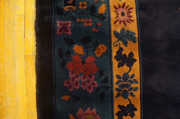 A multicolored high-pile rug featuring detailed teal and gold floral borders rests on bright yellow wood planks.