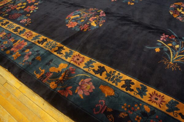 A plush navy rug with extensive multicolored floral patterns and gold borders rests on yellow hardwood flooring.
