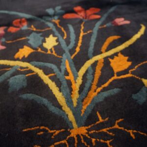 Plush navy rug detail showing a dimensional floral pattern in teal, orange, yellow, and pink.