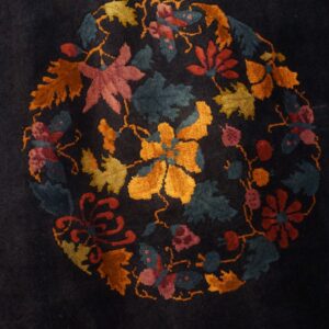 Dark blue rug with a plush pile displays a round central medallion of multicolor flowers and foliage.