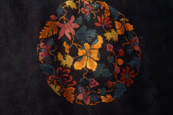 Dark blue rug with a plush pile displays a round central medallion of multicolor flowers and foliage.