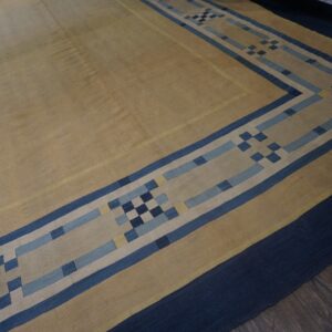Flatweave rug with a tan center and block-pattern border in blue, navy, and yellow on wood flooring.