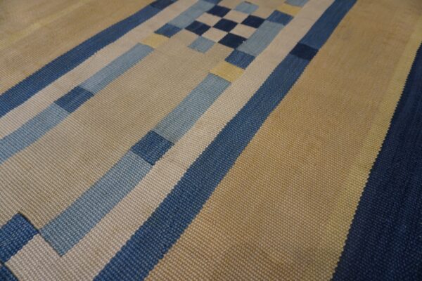 Geometric flatweave rug featuring wide tan and narrow blue, light blue, and cream stripes and block patterns.