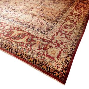 Ornate traditional rug corner displaying multi-layered borders and a floral field pattern in deep red and cream.