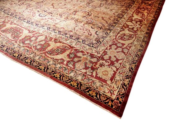 Ornate traditional rug corner displaying multi-layered borders and a floral field pattern in deep red and cream.
